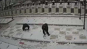 2 genç, karla kaplanan şehitlikteki mezar taşlarını temizledi